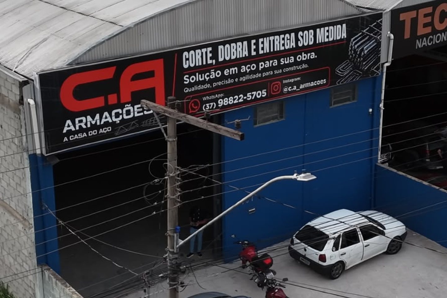 Galpão da CA Armações em Divinópolis, com a fachada azul e a faixa Corte, Dobra e Entrega Sob Medida